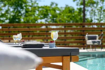 a table with two wine glasses next to a swimming pool at Aelia Luxury Villa in Sálakos