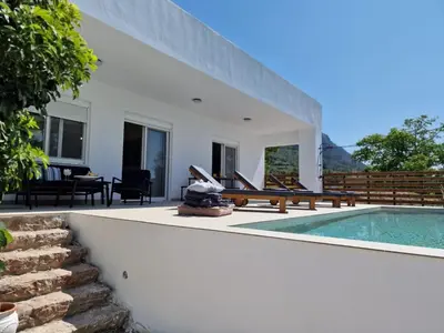a white house with a swimming pool and a patio at Aelia Luxury Villa in Sálakos