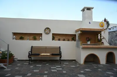 a bench in a patio with a clock on a wall at Anthias Beach Home in Archangelos