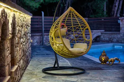 a wicker chair is sitting next to a pool at Glamorous Villa Nefeli in Koskinou