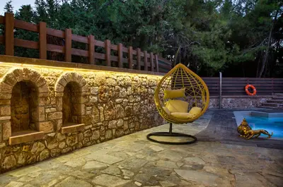 a wicker chair sitting next to a stone wall at Glamorous Villa Nefeli in Koskinou