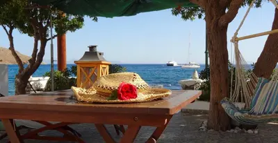 a table with a hat and a red rose on it at ANEMOESSA APTS in Livadia