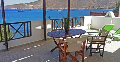 a table and chairs on a balcony with a view of the water at ANEMOESSA APTS in Livadia