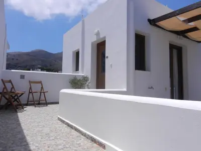 a white house with a balcony with mountains in the background at ANEMOESSA APTS in Livadia