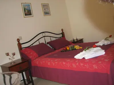 a bedroom with a red bed with towels on it at ANEMOESSA APTS in Livadia