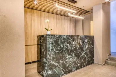 a lobby with a black marble counter with a plant on it at Astron Hotel Rhodes in Rhodes Town