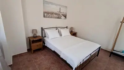 a bedroom with a bed with white sheets and pillows at Dimitra - Kattavia surf houses in Kattavía