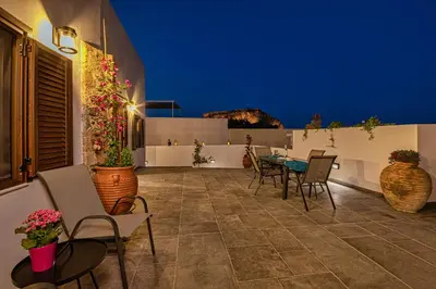 a patio with chairs and a table at night at Villa Danae - Lindos in Líndos