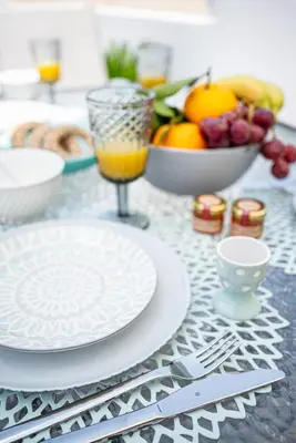 a table with plates and utensils and a bowl of fruit at Villa Danae - Lindos in Líndos