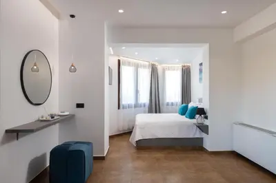 a white bedroom with a bed and a mirror at Waves of Blue in Koskinou