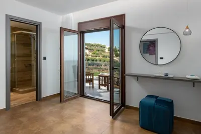 a room with a mirror and a door to a balcony at Waves of Blue in Koskinou