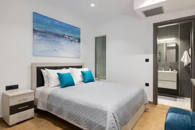 a bedroom with a large bed with blue pillows at Waves of Blue in Koskinou