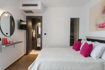 a bedroom with a large white bed with pink pillows at Waves of Blue in Koskinou