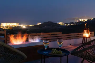 two glasses of wine on a balcony at night at Waves of Blue in Koskinou
