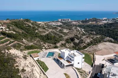 an aerial view of a house on a hill with the ocean at Waves of Blue in Koskinou
