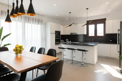 a kitchen with a wooden table and black and white at Waves of Blue in Koskinou