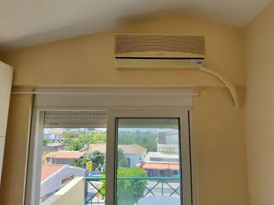 a room with a window with a air conditioner on the ceiling at orange in Ialyssos