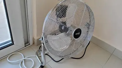 a white fan sitting on a floor next to a window at orange in Ialyssos
