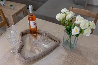 a bottle of alcohol and a vase of flowers on a table at Extreme House in Archangelos