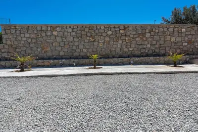 a stone wall with two palm trees on a sidewalk at Extreme House in Archangelos