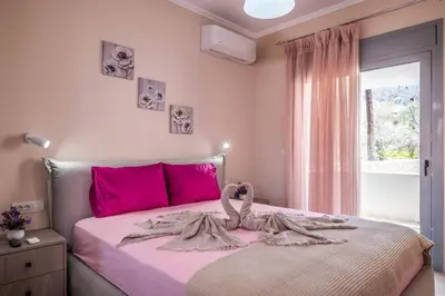 a pink bedroom with a large bed with pink pillows at Extreme House in Archangelos