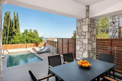 a patio with a table and chairs and a pool at Seaesta Villas in Koskinou