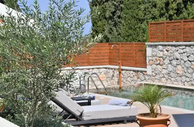 a pool with two lounge chairs next to a swimming pool at Seaesta Villas in Koskinou