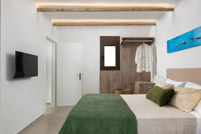 a bedroom with a bed and a tv on a wall at Seaesta Villas in Koskinou