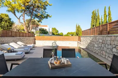 a patio with a table and chairs and a pool at Seaesta Villas in Koskinou
