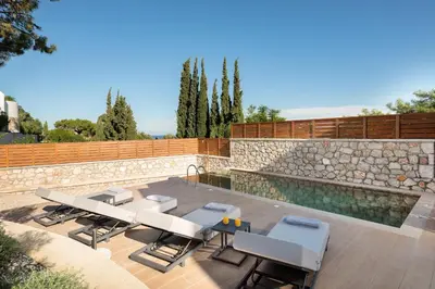 a patio with a table and chairs and a pool at Seaesta Villas in Koskinou