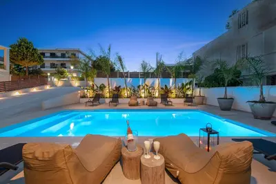 a swimming pool with chairs and a couch and a building at My Pixida Apartments in Rhodes Town