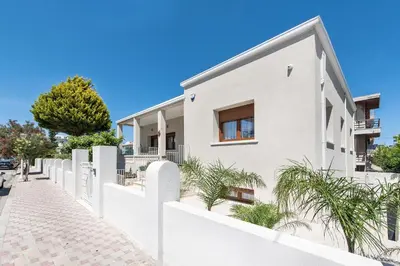 a white house with a white fence at My Pixida Apartments in Rhodes Town