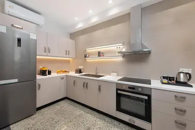 a kitchen with white cabinets and a stainless steel refrigerator at My Pixida Apartments in Rhodes Town