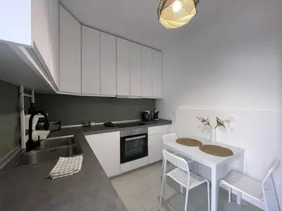 a kitchen with white cabinets and a table and chairs at Gravity Ialysos Scandi Suite in Ialyssos