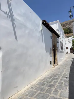 a white wall next to a cobblestone street at Villa AleNi Lindos in Líndos