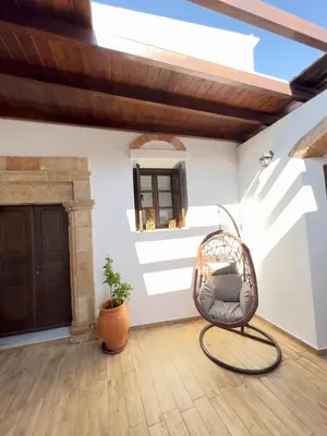 a wicker chair in a room with a door at Villa AleNi Lindos in Líndos