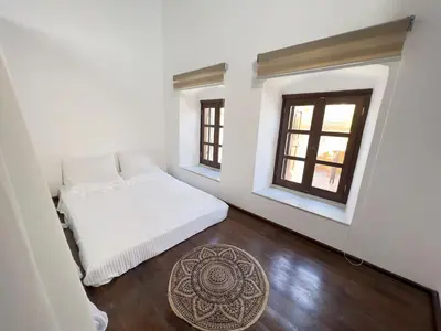 a bedroom with a white bed and two windows at Villa AleNi Lindos in Líndos