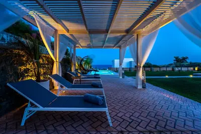 a patio with blue lounge chairs under a pergola at Heliophos Villa Aelia in Kiotari