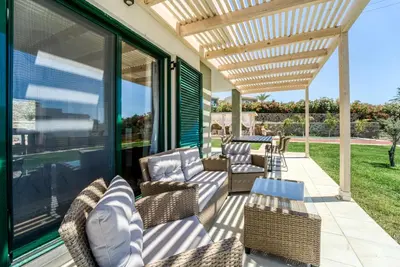 a patio with chairs and a wooden pergola at Heliophos Villa Aelia in Kiotari