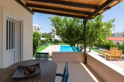 a patio with a table and chairs and a swimming pool at Villa Emerald in Asgourou