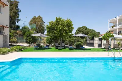 a swimming pool with chairs and umbrellas at a hotel at Villa Emerald in Asgourou