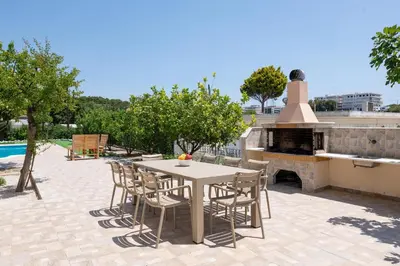 a patio with a table and chairs and a fireplace at Villa Emerald in Asgourou