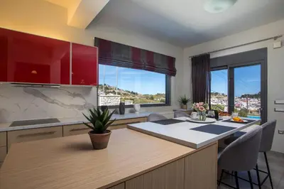 a kitchen with red cabinets and a table with chairs at High View Villa in Afantou
