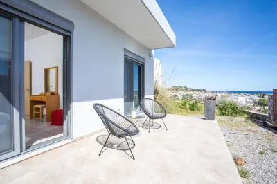 two chairs sitting on the balcony of a house at High View Villa in Afantou