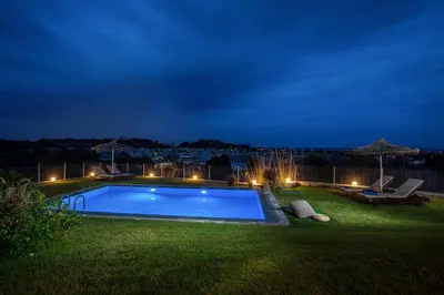 a swimming pool in a yard at night at High View Villa in Afantou
