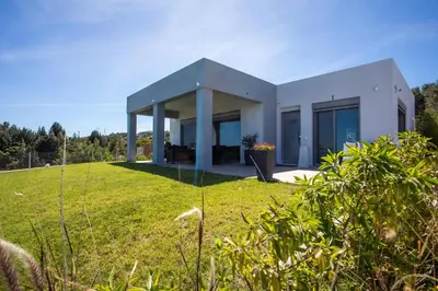 a white house on a grassy field at High View Villa in Afantou