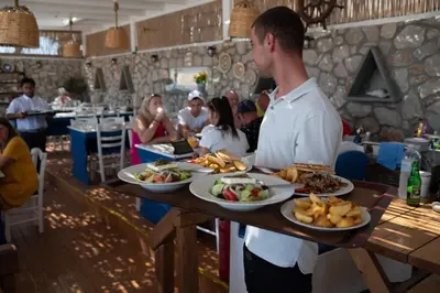 a man holding a table with plates of food at Prasonisi Lighthouse Boutique Hotel in Prasonisi