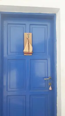 a blue door with a small boat on it at Pavlos Rooms in Livadia
