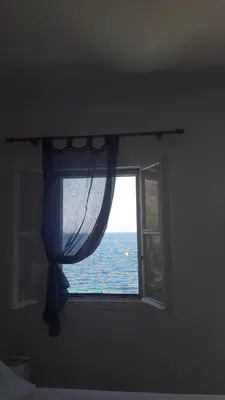 a window in a bedroom with a view of the ocean at Pavlos Rooms in Livadia