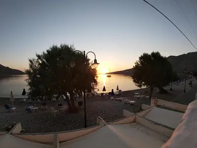 a view of a beach with trees and a sunset at Pavlos Rooms in Livadia